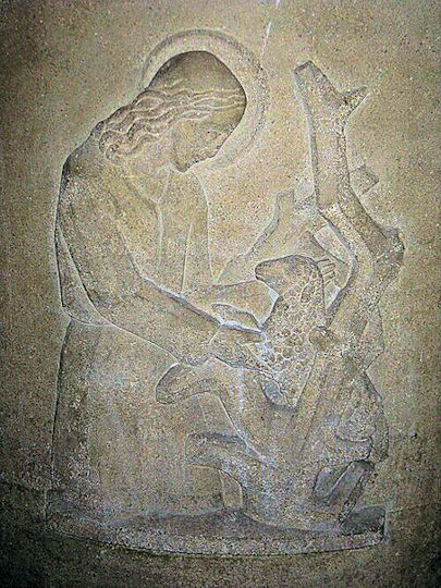 a stone relief carving showing a shepherd finding a lamb tangled up in a bush