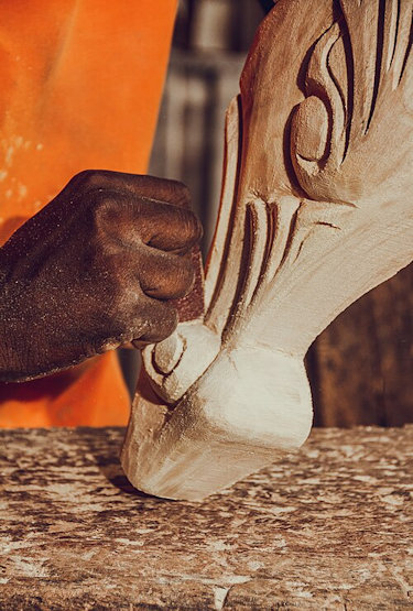 Young man's hand carving a wooden chair leg
