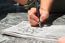 hand filling out crossword puzzle
