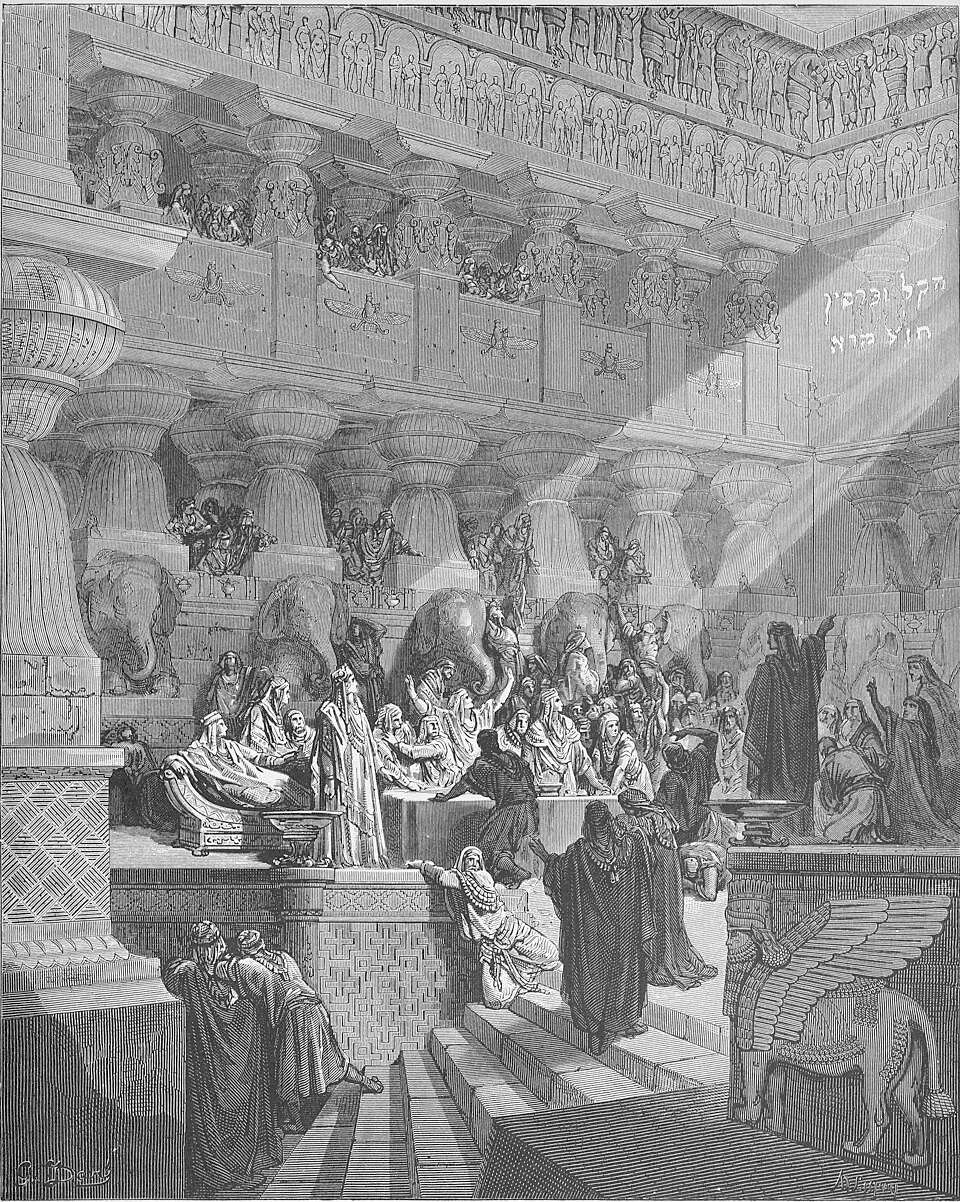 Daniel standing before the king and his advisors and pointing to Hebrew writing that appeared high up on the wall