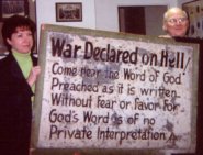 photo of two people holding an old sign that says, War declared on hell.